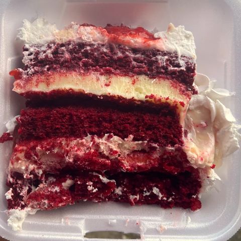 Fatia de red velvet na embalagem: massa vermelha, creme branco de cream cheese e morango